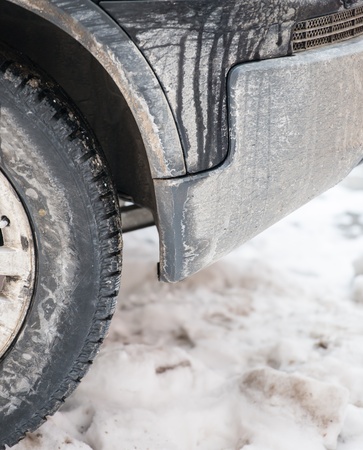 dirty car wheel stands on winter snowy roadの写真素材