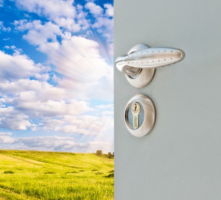 open door with a view of green meadow illuminated by bright sunshineの写真素材