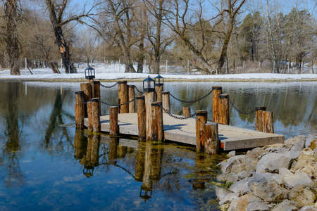 wooden bridge on pillars with chain pond in early springの写真素材