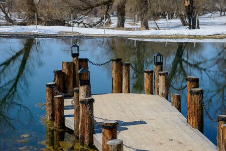 wooden bridge on pillars with chain pond in early springの写真素材