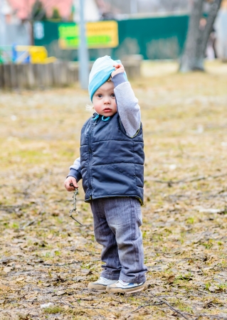 little boy standing in the park with his hand raisedの写真素材
