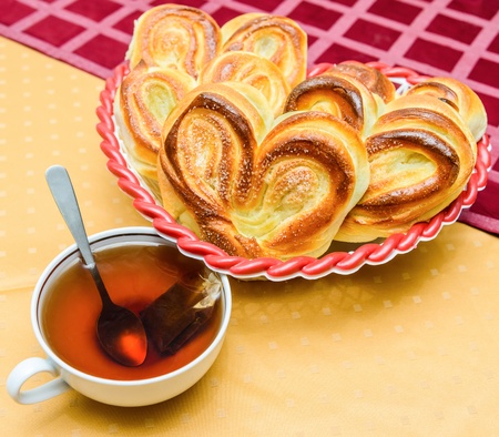 cup of hot tea with buns on a table covered with a tableclothの写真素材