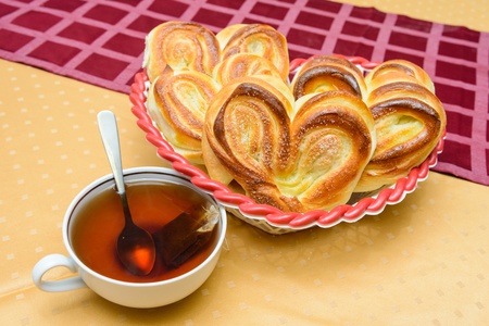 cup of hot tea with buns on a table covered with a tableclothの写真素材