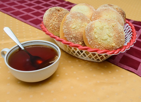cup of hot tea with buns on a table covered with a tableclothの写真素材