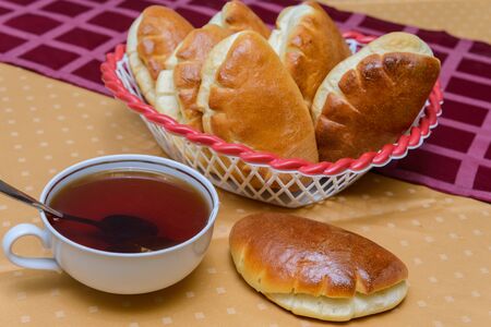 cup of hot tea with buns on a table covered with a tableclothの写真素材