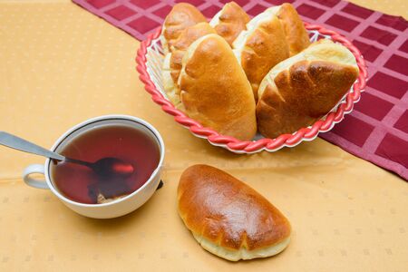 cup of hot tea with buns on a table covered with a tableclothの写真素材