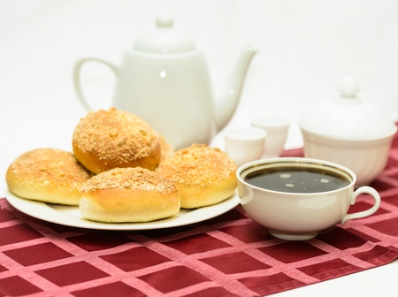 cup of hot tea with buns on a table covered with a tableclothの写真素材