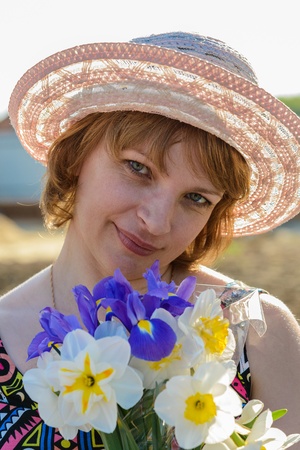 middle-aged woman in a hat holding a bouquet of flowers narcissusの写真素材