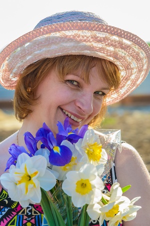 middle-aged woman in a hat holding a bouquet of flowers narcissusの写真素材