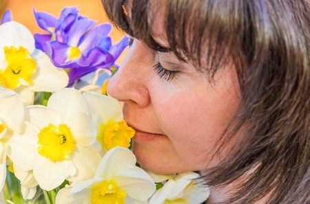 middle-aged woman smelling a bouquet of flowers narcissusの写真素材