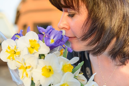 middle-aged woman smelling a bouquet of flowers narcissusの写真素材