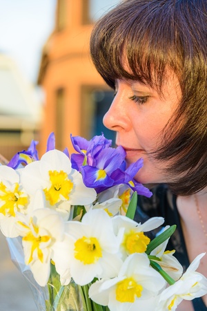 middle-aged woman smelling a bouquet of flowers narcissusの写真素材