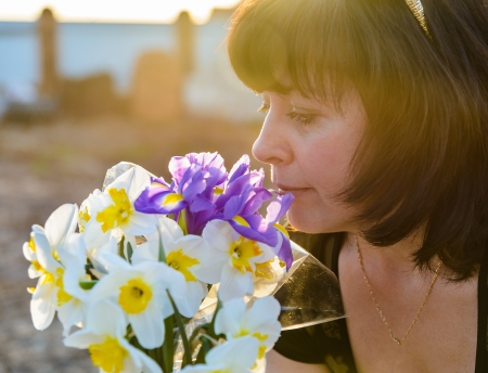 middle-aged woman smelling a bouquet of flowers narcissusの写真素材