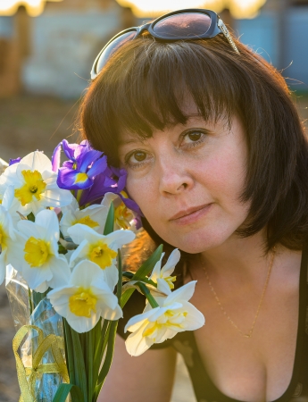 middle-aged woman smelling a bouquet of flowers narcissusの写真素材