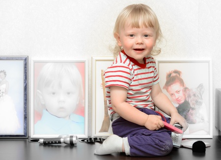portrait of a little boy in a striped shirt against the background of photosの写真素材