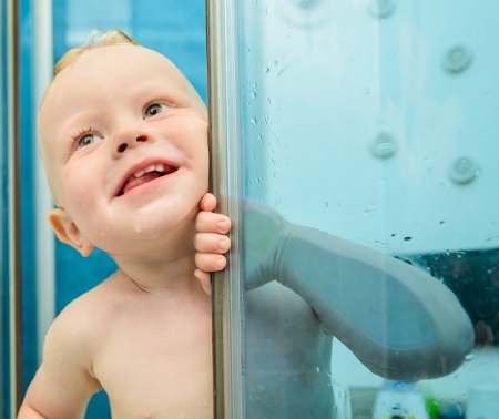 small red-haired boy is bathed in the showerの写真素材