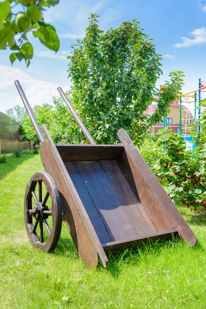 old brown wooden cart on the green lawn in the gardenの写真素材