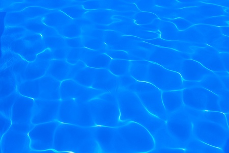 background of blue water in the pool with the reflection of the sunの写真素材