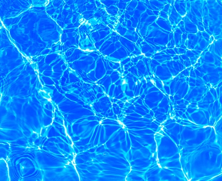 background of blue water in the pool with the reflection of the sunの写真素材