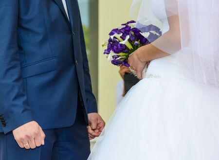 the groom in a blue suit and a bride holding a wedding bouquet of flowersの写真素材
