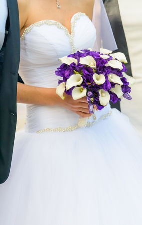 bride in a white dress holding a wedding bouquet of flowersの写真素材