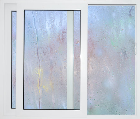 White window with blue curtains on a rainy dayの写真素材