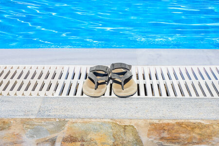 summer leather sandals are on the edge of the swimming poolの写真素材