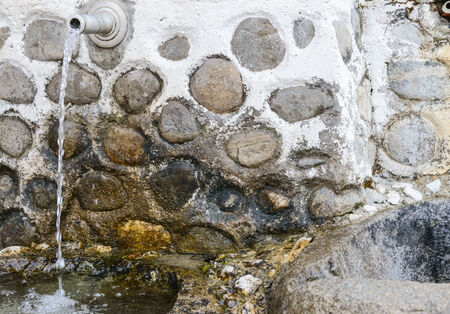 iron pipe out of the ground with spring waterの写真素材