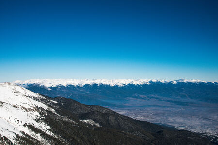 Mountain landscape in sunny winter frosty day with blue clear sky. 
Coniferous trees grow on the slopes lit sunの写真素材