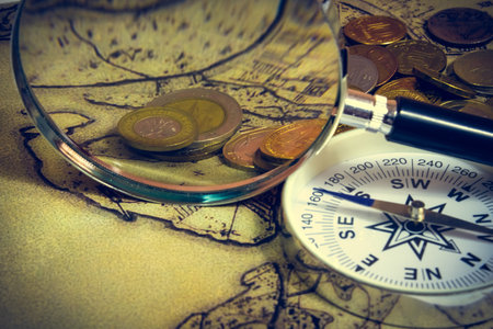 compass and magnifying glass gold color on the old map with coins