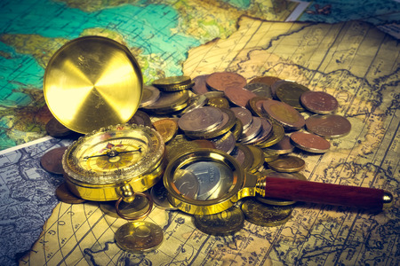 compass and magnifying glass gold color on the old map with coinsの写真素材