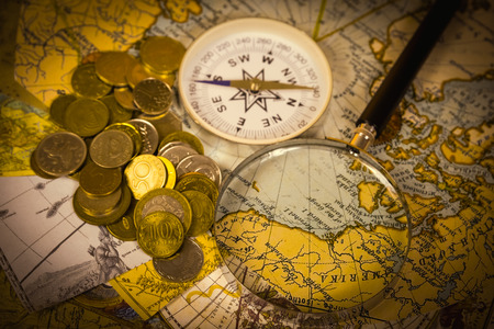 compass and magnifying glass gold color on the old map with coinsの写真素材