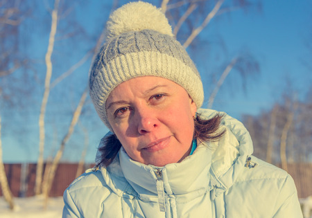 middle-aged woman in a ski jacket and a hat with pompomの写真素材