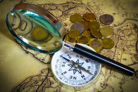 compass and magnifying glass gold color on the old map with coins