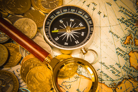 compass and magnifying glass gold color on the old map with coinsの写真素材