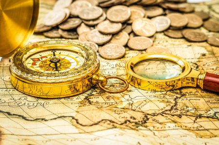 compass and magnifying glass gold color on the old map with coinsの写真素材
