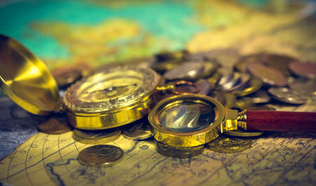 compass and magnifying glass gold color on the old map with coinsの写真素材
