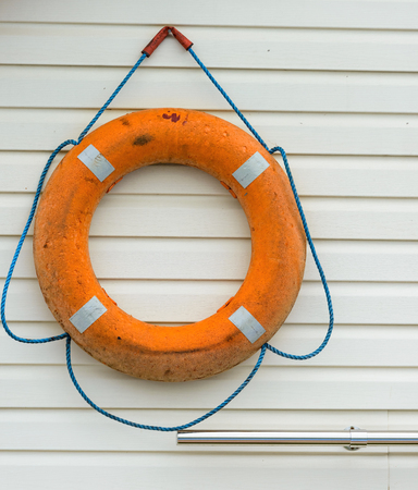 orange life buoy with rope hanging around the poolの写真素材