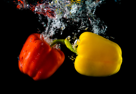 Pepper falls in water with bubbles on black backgroundの写真素材