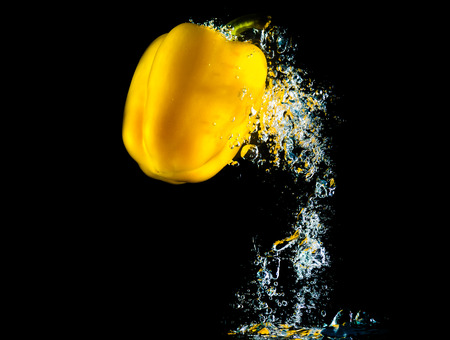 Pepper falls in water with bubbles on black backgroundの写真素材