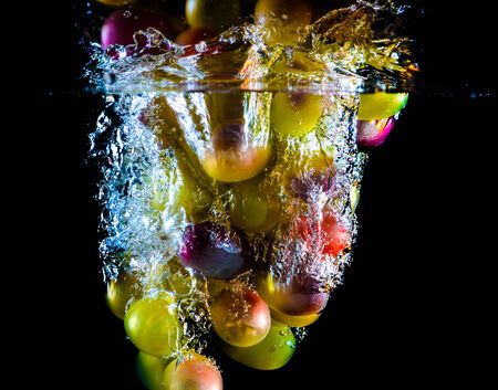 bunch of ripe grapes in water on a black backgroundの写真素材