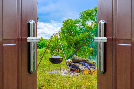 kettle on a tripod hanging around a bonfire open doorの写真素材