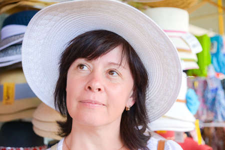 Happy middle aged brunette with hat in storeの写真素材