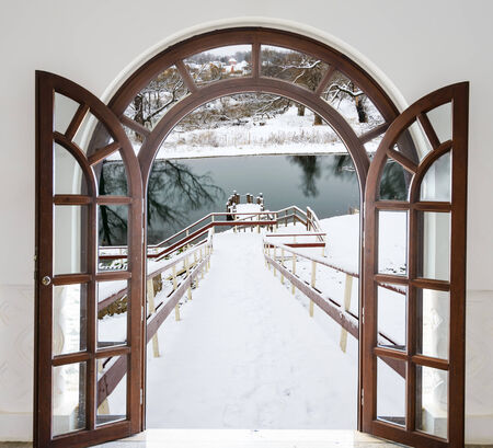 open door arch access to the stairs down winter covered with snowの写真素材