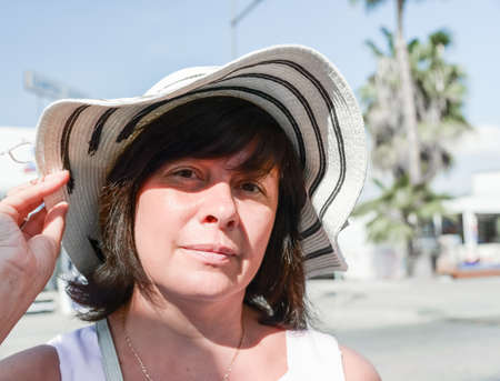 Happy middle aged brunette with hat in storeの写真素材