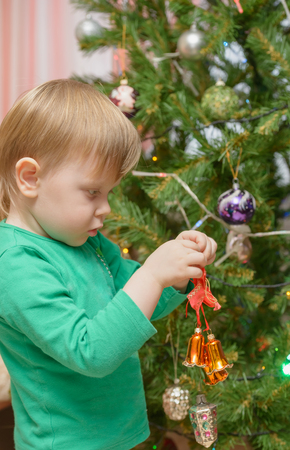 blond little boy dresses up Christmas tree toysの写真素材