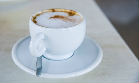 cup of cappuccino with cinnamon on the table with a saucer and spoonの写真素材