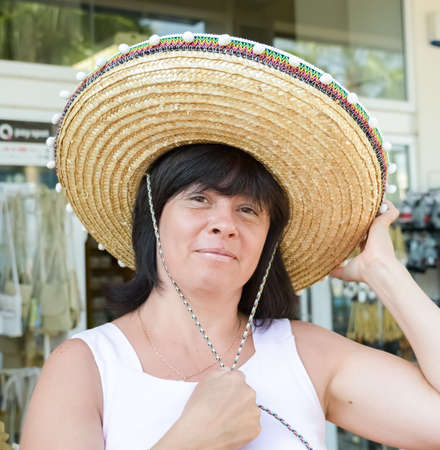 Happy middle aged brunette with hat in storeの写真素材