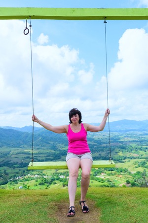 woman sitting on a swing high in the summer dayの写真素材