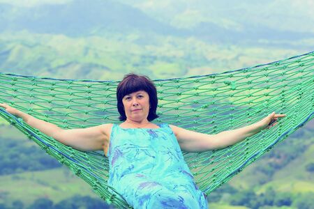 Brunette middle aged woman riding on a swing suspended highの写真素材